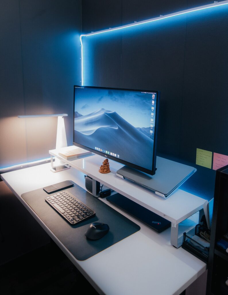 Organized workspace featuring a sleek monitor, keyboard, and ambient lighting for a tech-savvy environment.