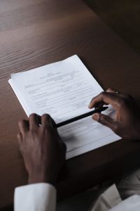 Hands holding a pen and reviewing a contract on a wooden table, creating a professional business setting.